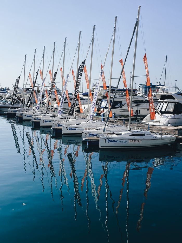 A peaceful marina scene featuring sailboats docked in calm waters with clear reflections.